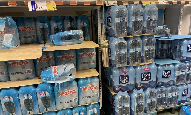 Scaffali pieni di bottiglie d'acqua in pacchi multipli. Il prezzo di 73 centesimi per una bottiglia d'acqua in crociera è un affare!