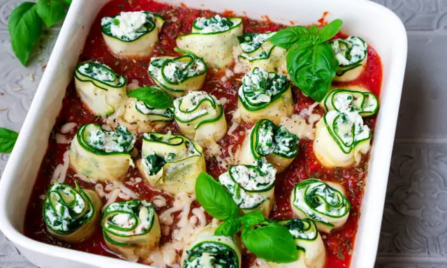 Zucchini-Cannelloni mit Ricotta-Spinat-Füllung in Tomatensauce, garniert mit frischem Basilikum.
