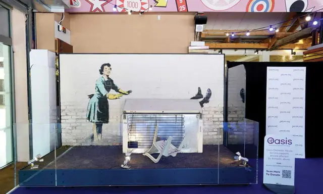 Banksy's "Girl with Balloon" installation, a prime example of art investment, displayed with a fridge and chair.