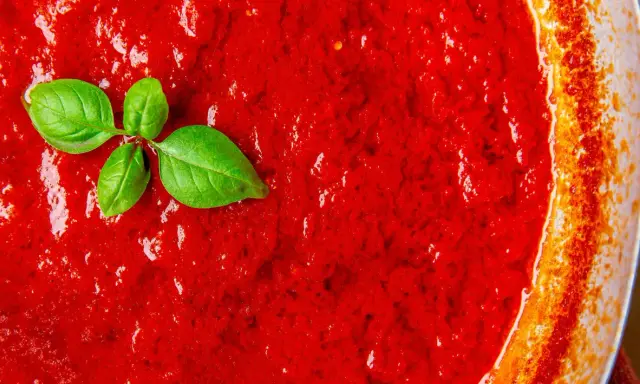 San Marzano Tomatensoße, perfekt für jedes Rezept. Ein Hauch frisches Basilikum rundet das Bild ab.