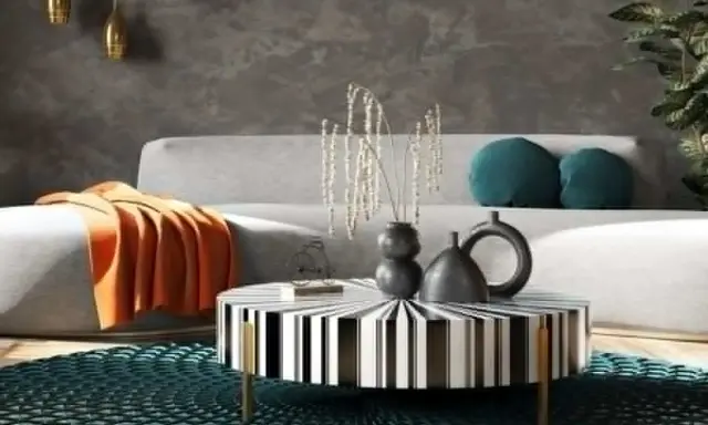 Nowoczesny salon w stylu feng shui z szarą kanapą, pomarańczowym kocem, czarno-białym stolikiem i turkusową podłogą.