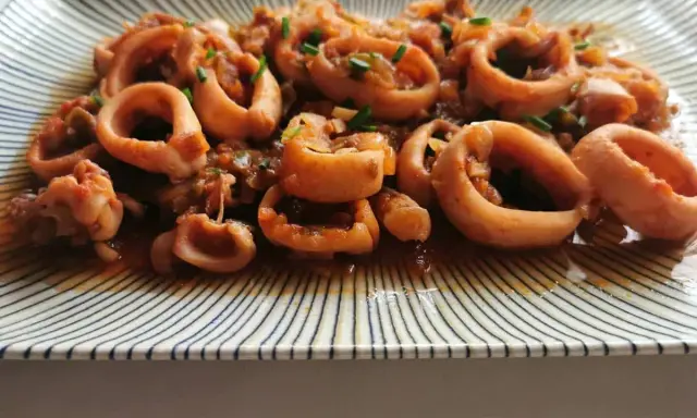 Calamares a la riojana, un plato tradicional español con aros de calamar cocinados en una sabrosa salsa de tomate y pimientos.