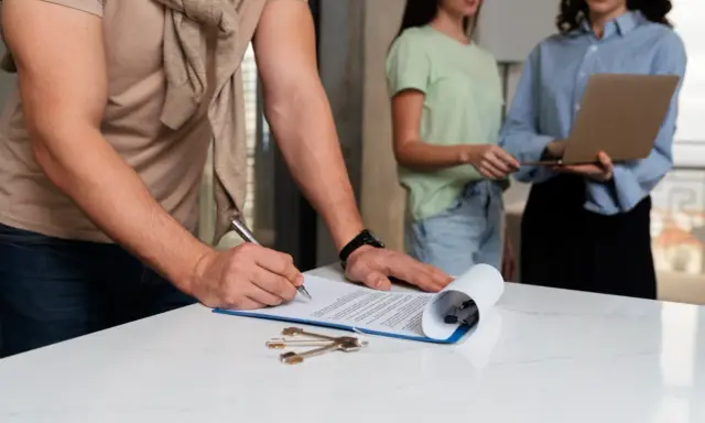 Firma de un contrato, quizás relacionado con el **artículo 32 de la ley de arrendamientos urbanos**, con llaves sobre la mesa.