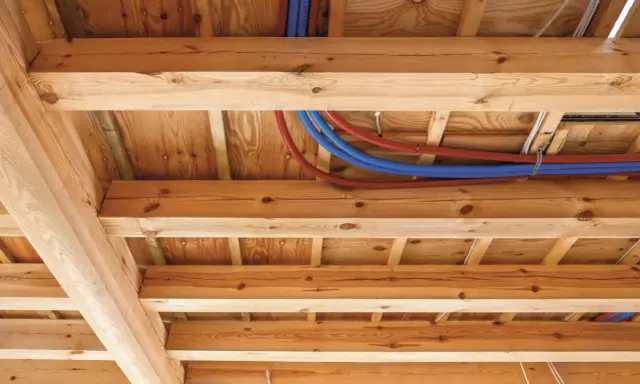 Drewniane belki stropowe z widocznymi instalacjami hydraulicznymi i elektrycznymi.