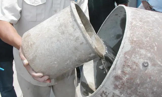 Se vierte agua de un cubo a otro, preparándose para proporcionar cemento y agua.
