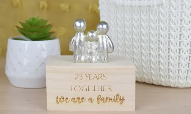 Srebrna figurka rodziny na drewnianym pudełku z napisem "23 YEARS TOGETHER We are a family". Idealny prezent na 23 rocznicę ślubu.