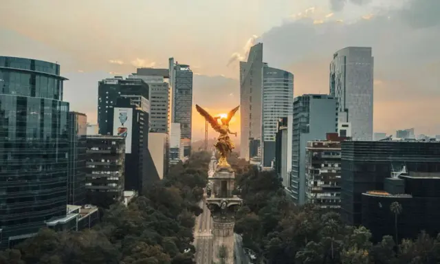 Goldene Viktoria-Statue im Sonnenuntergang, umgeben von modernen Wolkenkratzern in Mexico City.