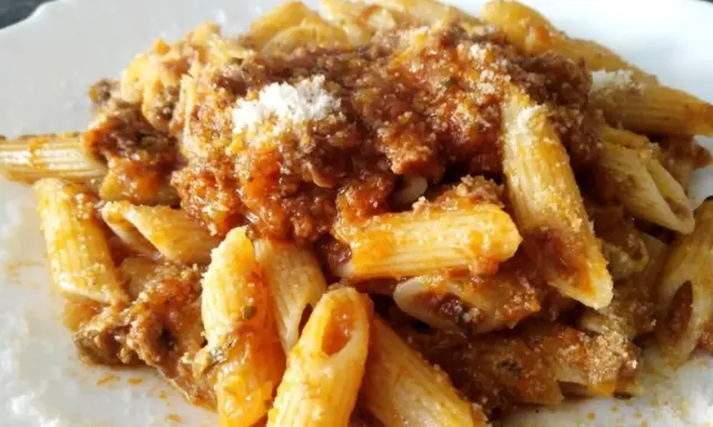 Penne al ragù di cinghiale, un piatto ricco e saporito, condito con abbondante sugo e una spolverata di parmigiano.