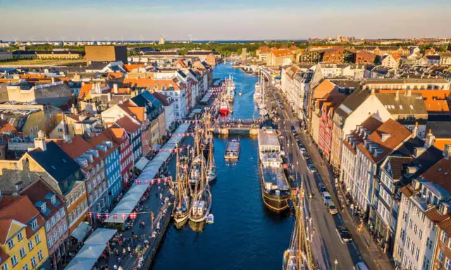 Navigazione nel porto di Copenaghen, con case colorate, barche a vela e un vivace lungomare.