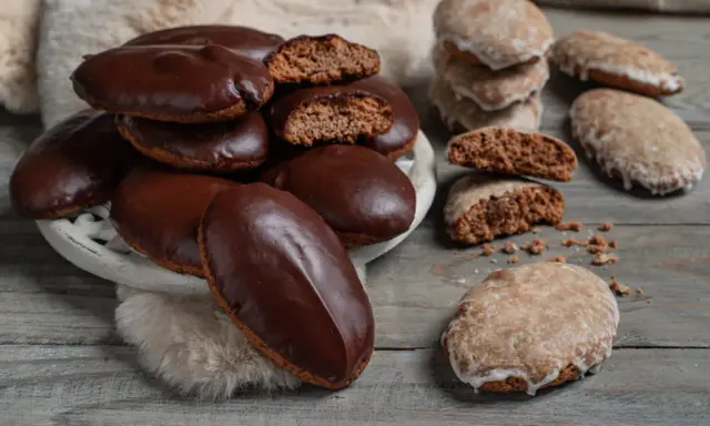 Biscotti tipici calabresi, alcuni ricoperti di cioccolato fondente, altri glassati, su un tavolo di legno.