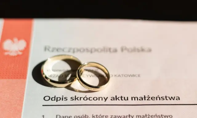 Dwa złote obrączki na odpisie skróconym aktu małżeństwa. Dokument potwierdza, ile jest ważny akt małżeństwa.