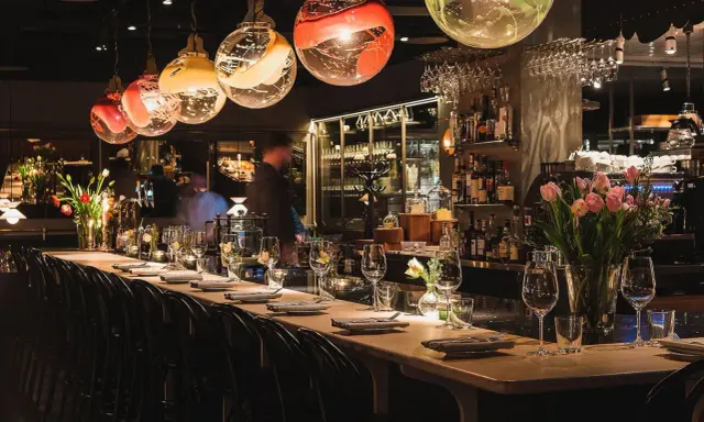 Elegant bar i en michelin restaurang Stockholm. Vackra glaslampor, blommor och uppdukade bord skapar en lyxig atmosfär.
