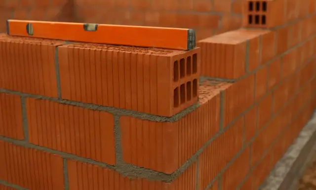 Nivel de burbuja sobre ladrillos huecos, mostrando la construcción de varios tipos de tabiques interiores.