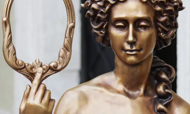 Bronzestatue der Aphrodite, die einen verzierten Spiegel hält. Ihr lockiges Haar und ihr sanfter Blick unterstreichen ihr klassisches Aphrodite-Aussehen.