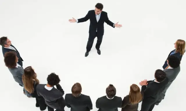 Un líder inspira a su equipo. Un grupo de personas en círculo escuchan atentamente a un hombre que demuestra master liderazgo y gestión de equipos.