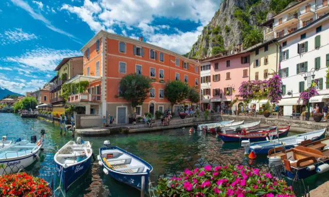 Colorate case sul lungolago di Limone sul Garda, con barche ormeggiate e fiori vivaci. Un luogo incantevole da scoprire, perfetto per capire cosa visitare a Limone sul Garda.