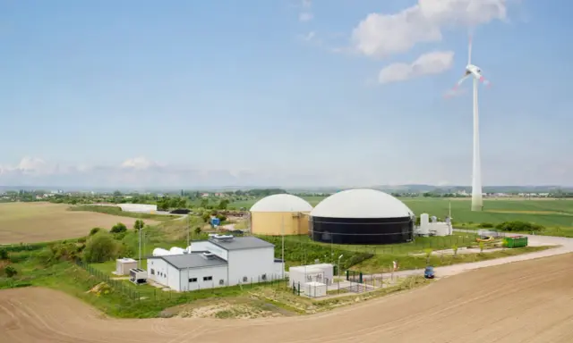 Biogasanlage mit großen Speichern und Windrad. Hier wird Energie erzeugt und für den biogas transportieren vorbereitet.