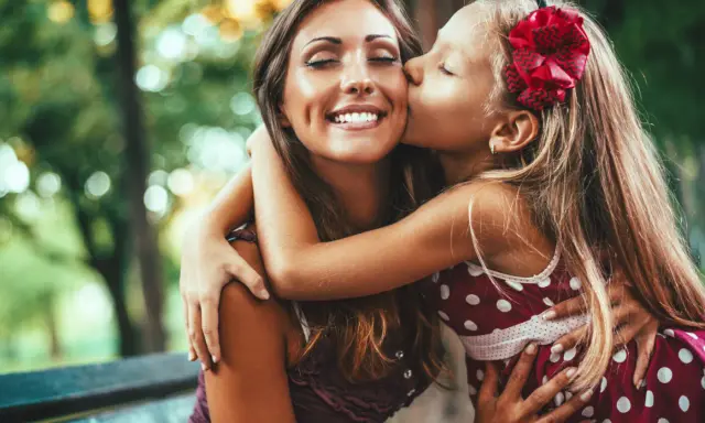 En flicka ger sin mamma en kyss på kinden. En vacker bild av kärlek och **compassion svenska**.