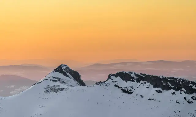 Giewont zimą o zachodzie słońca. Ośnieżone szczyty Tatr w odcieniach pomarańczy i różu.