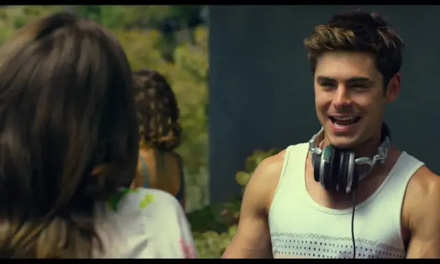 Il cast di We Are Your Friends, Zac Efron con le cuffie al collo, sorride mentre parla con qualcuno fuori campo.