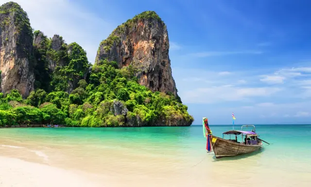 Idealna pogoda na Phuket w listopadzie: spokojne morze, piaszczysta plaża i tradycyjna łódź.