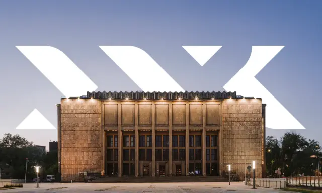 Monumentalna fasada Muzeum Narodowego w Krakowie przy Alei 3 Maja, oświetlona wieczorem.