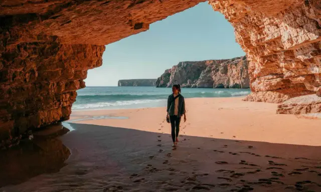Frauen spazieren am Strand unter Felsbögen, ein perfekter Moment auf einer 14-tägigen Rundreise Portugal.