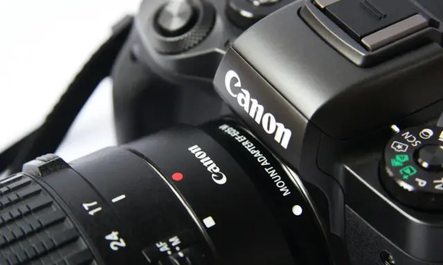 Zbliżenie na czarny aparat cyfrowy Canon z obiektywem.
