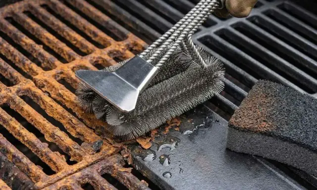 Cepillo metálico limpiando parrilla barbacoa oxidada. Un guante marrón sujeta el cepillo mientras elimina el óxido y la suciedad.