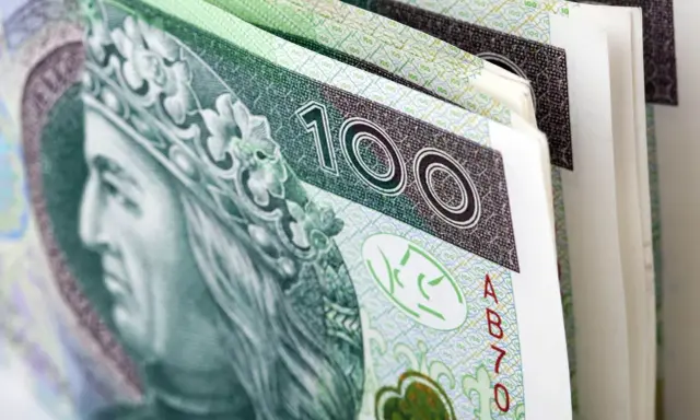 Stos banknotów 100 zł, symbolizujący premię uznaniową. Król na banknocie wygląda jakby cieszył się z dodatkowych pieniędzy.