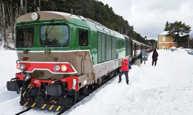 Treno della Transiberiana d'Abruzzo in sosta, con passeggeri sulla neve. Le tappe di questo viaggio unico tra montagne innevate.
