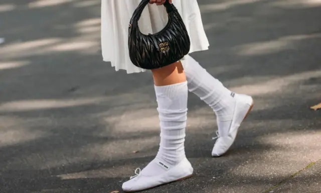 Piernas con bailarinas blancas y calcetines blancos arrugados, un look chic para bailarinas con calcetines.