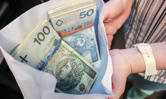 Koperta z plikiem banknotów 100 i 50 zł. Ile dać na 50 urodziny? Tyle pieniędzy to dobry prezent!