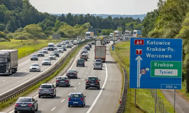 Korek na autostradzie A4 w kierunku Katowic. Samochody stoją w długim sznurze, a znaki drogowe wskazują drogę do Krakowa i Tynca.