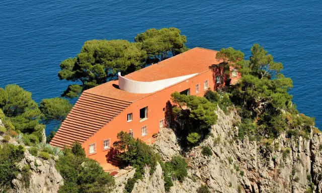 Villa Malaparte interni: arancione, sul mare, con scalinata e alberi.