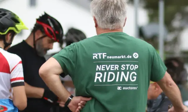 Männer in Radlerkleidung, einer trägt ein grünes T-Shirt mit der Aufschrift "RTFneumarkt.de NEVER STOP RIDING".