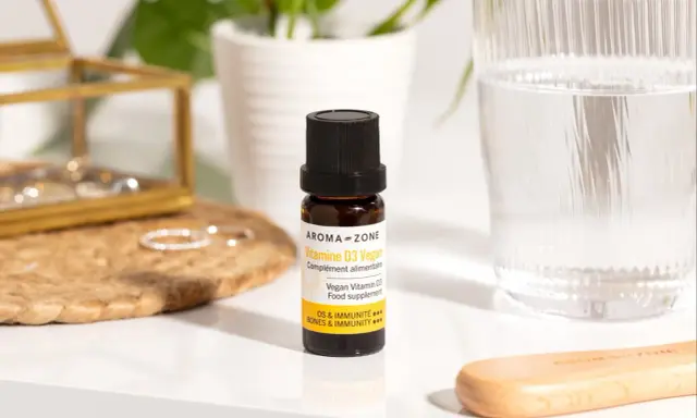 Un flacon de vitamine D3 vegan, un remède de grand-mère pour pallier le manque de vitamine D, à côté d'un verre d'eau.