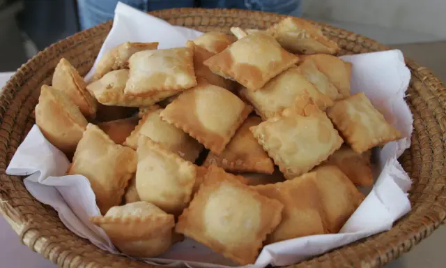 Un panier rempli de beignets dorés, une spécialité des Hautes-Alpes, prêts à être dégustés.