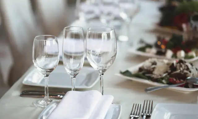Trois verres à eau sont disposés sur une table dressée, prêts pour un repas.