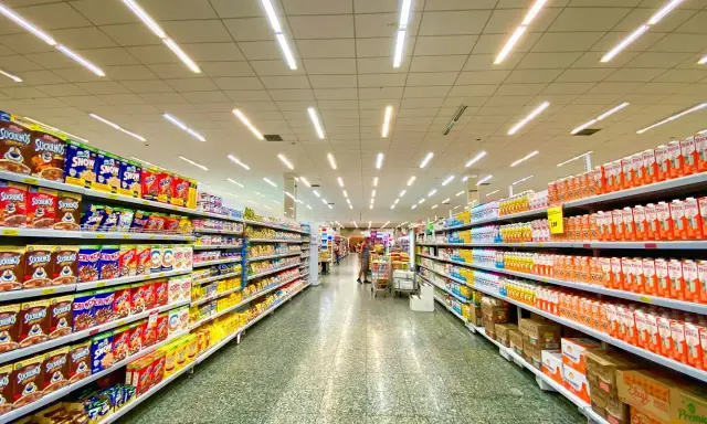 Alejka w supermarketach, pełna produktów na półkach. Widać kartony z płatkami śniadaniowymi i napojami. To typowe sklepy po angielsku, gdzie można znaleźć wszystko.