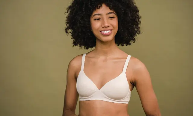 Donna sorridente con un reggiseno color carne. Un reggiseno troppo stretto conseguenze possono essere scomode, ma questo sembra comodo.