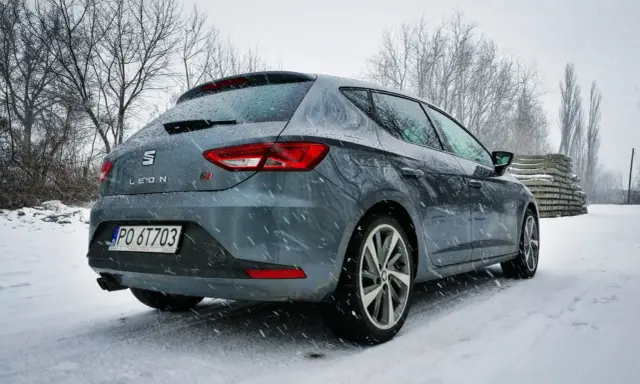 Szary Seat Leon FR w zimowej scenerii, pokryty śniegiem.