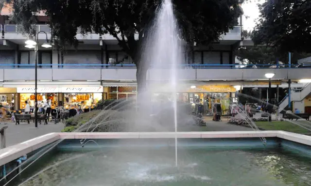 Fontana z fontanną w centrum Lido di Savio, z widokiem na sklepy i drzewa.