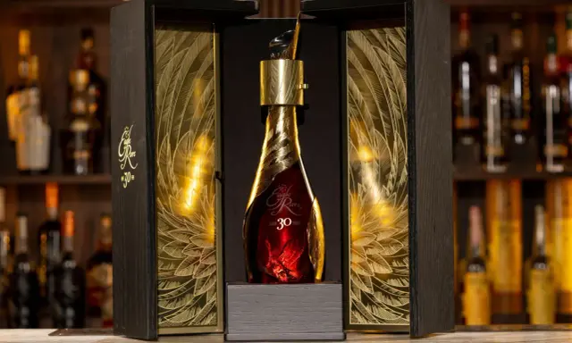 Elegancka, złota butelka z 30 letnią whisky Eagle Rare w ozdobnym, drewnianym pudełku z motywem piór.