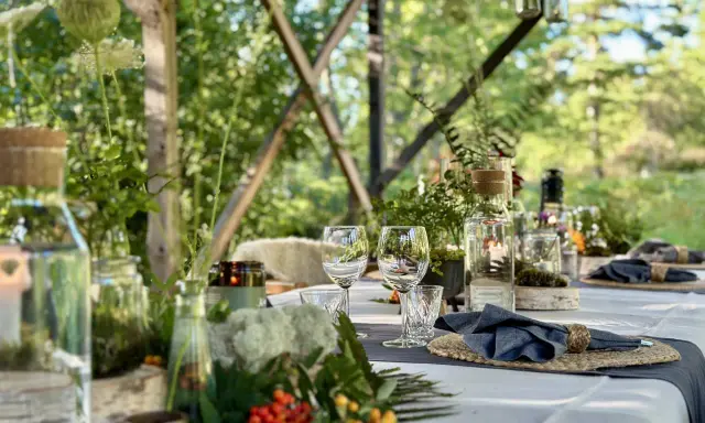 Vacker dukning för en restaurang i skogen. Glas, servetter och dekorationer av naturmaterial skapar en inbjudande atmosfär.