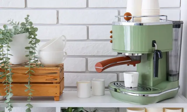Máquina de café verde estilo retro, tazas apiladas y planta colgante. Un rincón del café listo para disfrutar.