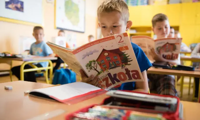 Chłopiec z zapałem czyta podręcznik "Nasza Szkoła". To dobry start dla każdego ucznia, by z radością poznawać świat.