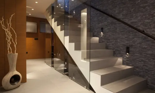 Nowoczesna klatka schodowa inspiracje: szkło, kamień i drewno tworzą elegancką przestrzeń.