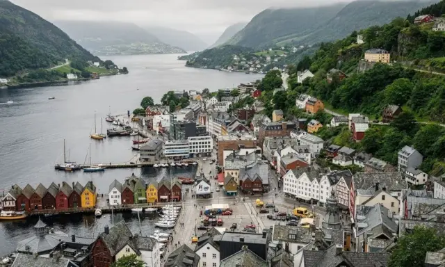 Il pittoresco porto di Bergen, con le sue case colorate affacciate sull'acqua e le colline verdi che fanno da sfondo.