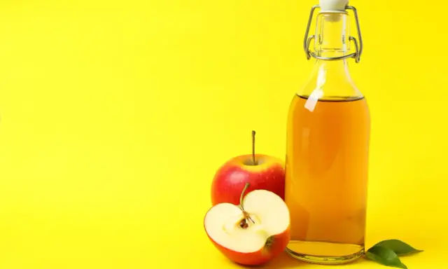 Bouteille de vinaigre de cidre et pommes rouges, un remède naturel pour l'urticaire.